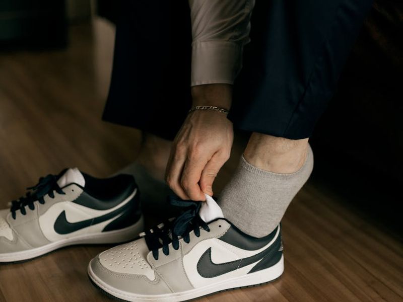 A close-up of a person's athletic shoes on a dark floor, ready for action.